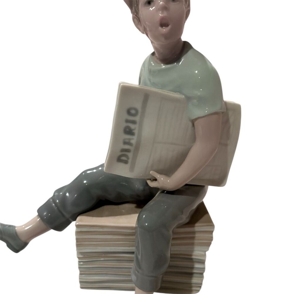 NAO by Lladro Porcelain Figurine Newsboy Sitting on Newspaper Pile